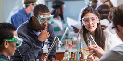 Young adult students of various ethnic backgrounds doing a chemistry experiment in class