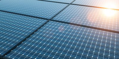 close up image of black solar panels covered in a white grid pattern, reflecting the sun in the top right corner