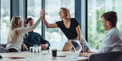 Female professionals high fiving during a work meeting