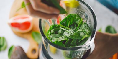 spinach being added to a blender to make a smoothie