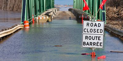 A flooded bridge with a sign indicating the road is closed