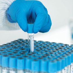 The hand of a young Asian woman holding a test tube in a lab