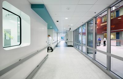 Researcher in white lab coat walking through biosafety lab corridor