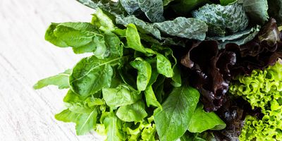 a varied bunch of leafy greens on a white marble countertop