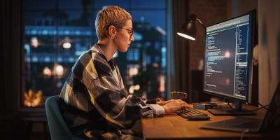 Young woman working on a computer code at a desk