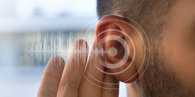 a photo representing hearing, showing a man's ear with his hand behind it, overlayed with a circular target and audiowaveforms