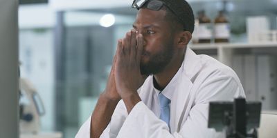 Young scientist sits in the lab looking stressed