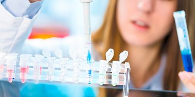 A female scientist piping liquid into a test tube.