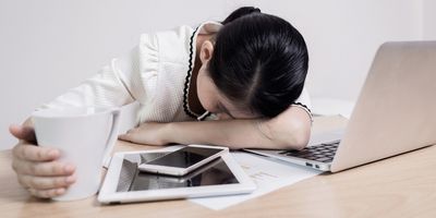 Woman resting head on desk in front of computer