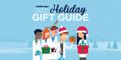 Lab Manager characters Linda the Lab Manager and her team stand beneath the text "Lab Manager 2021 Holiday Gift Guide." They are exchanging presents and wearing various Christmas attire along with their lab coats.