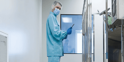 Scientist in PPE stands in a lab looking at the camera