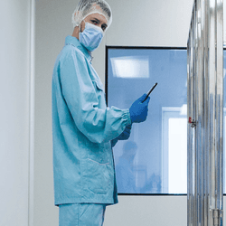 Scientist in PPE stands in a lab looking at the camera