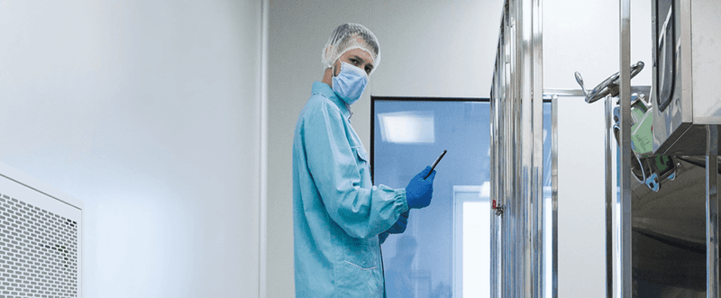 Scientist in PPE stands in a lab looking at the camera