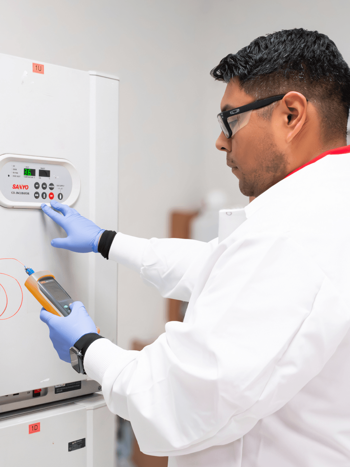 A lab technician pushes buttons on a lab incubator